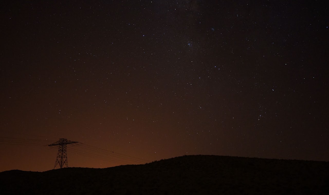 Starry night above a silhouetted hillside